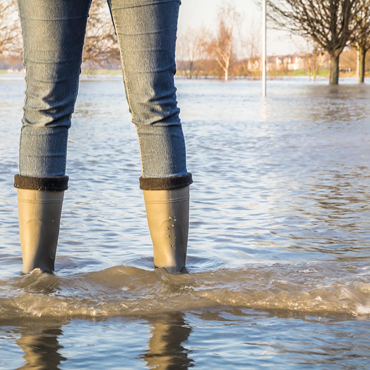 Person in jeans and Wellington boots standing in floodwater