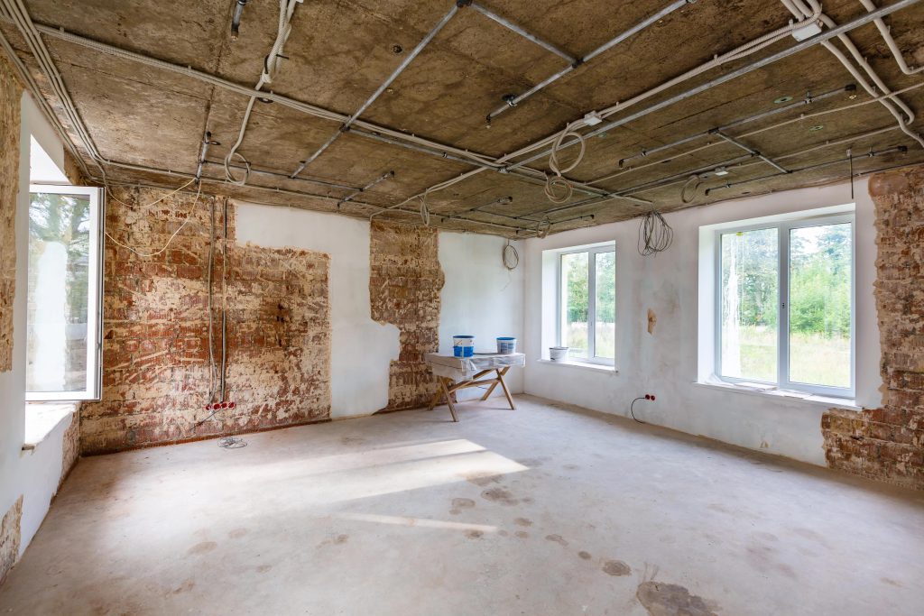 Interior room under repair with exposed brick and concrete ceiling